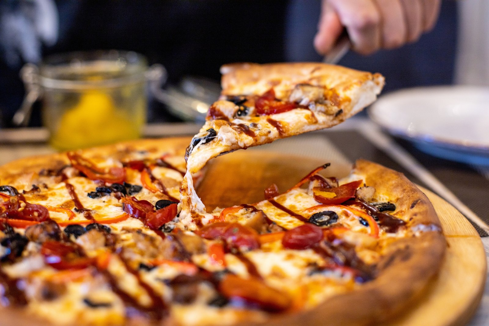 Hand of man holding slice of pizza over table against restaurant background